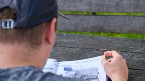 Mlad moški bere knjigo od zadaj