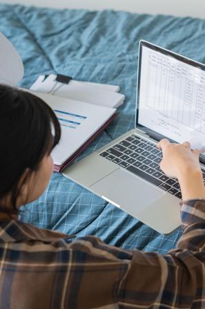 Mlada punca študentka z računalnikom na postelji