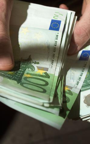 Moški v roki drži denar evre