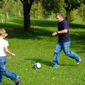 oče in sin igrata nogomet na travi