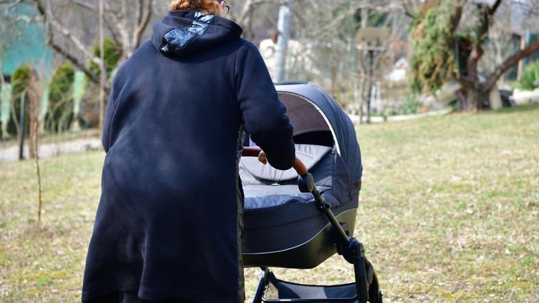 Ženska z dojenčkom v vozičku na sprehodu