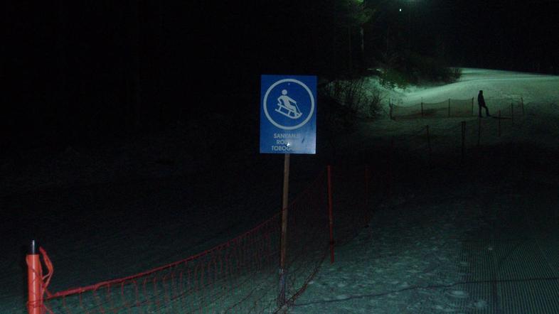 Tudi ko se prižgejo reflektorji, je večina ozke proge v temi, smučarji pa smučaj