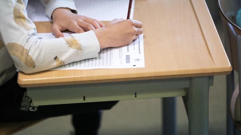 učenec sedi za mizo v razredu in piše test