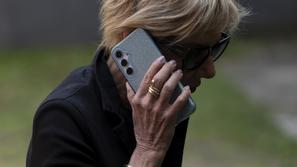 Starejša ženska z očali in telefonom v roki