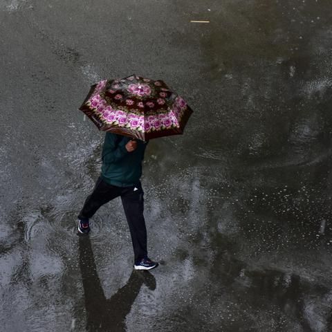 moški z dežnikom hodi po ulici dež